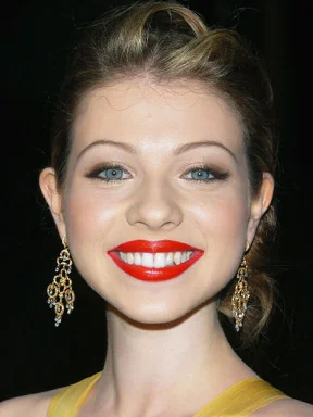 Michelle Trachtenberg smiling with red lipstick and earrings