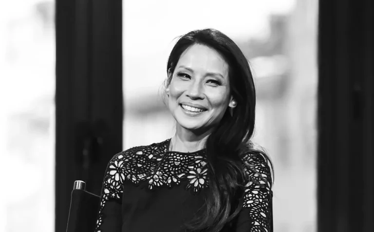 Lucy Liu smiling in a black lace dress at an event.