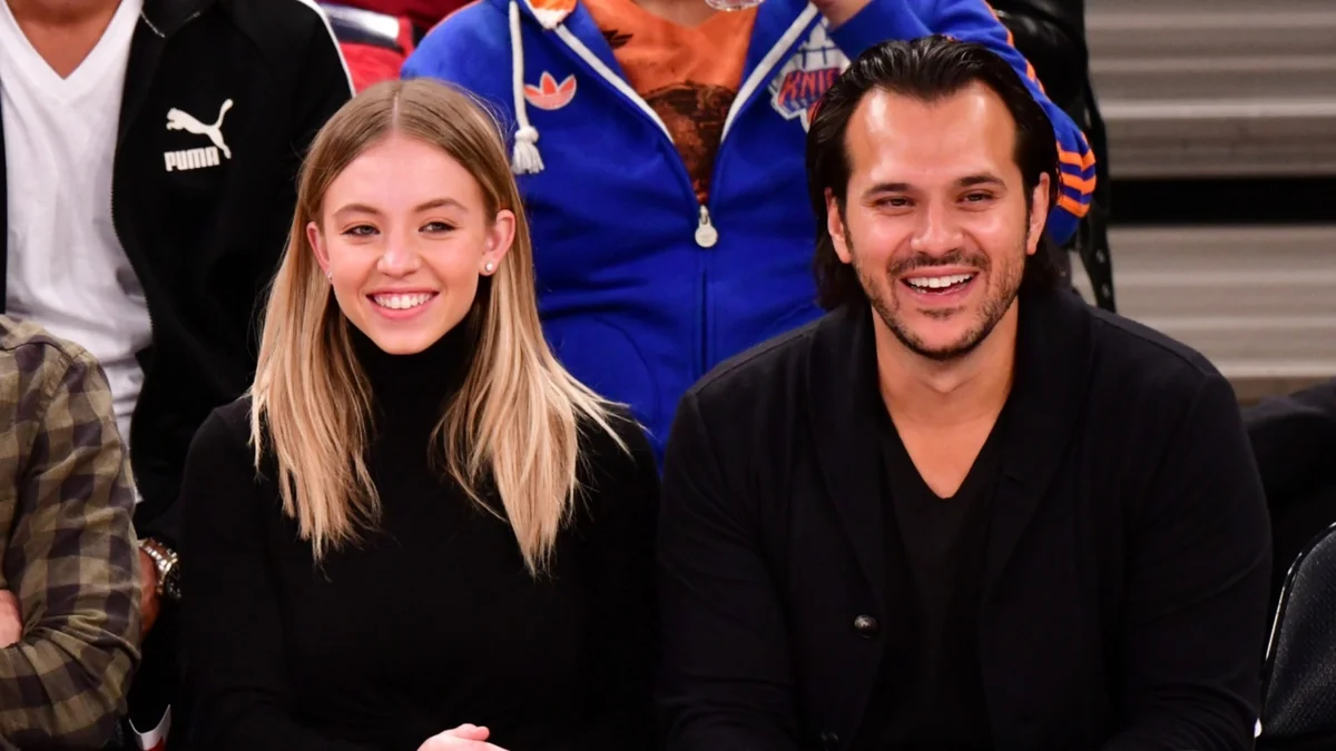 Jonathan Davino and Sydney Sweeney smiling courtside, reflecting their playful relationship dynamic.