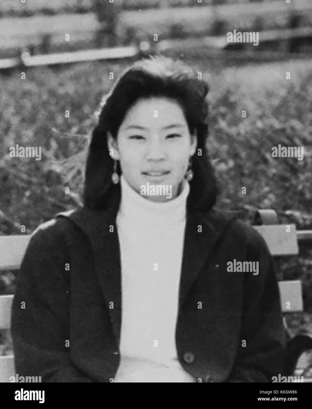 Young Lucy Liu sitting on a bench.