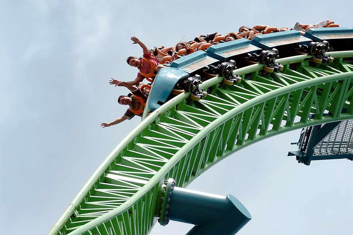 Excited riders on roller coaster, highlighting thrill and risks like 'died at Six Flags'.