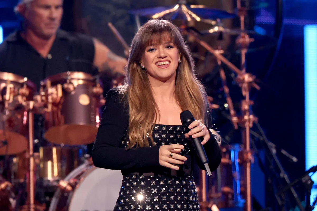 Kelly Clarkson smiling on stage, embodying her joyful songs.