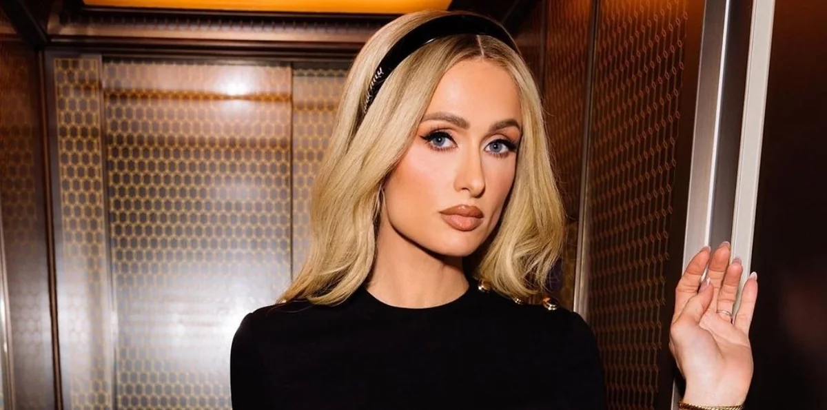 Paris Hilton posing in an elevator, showcasing her style and net worth.