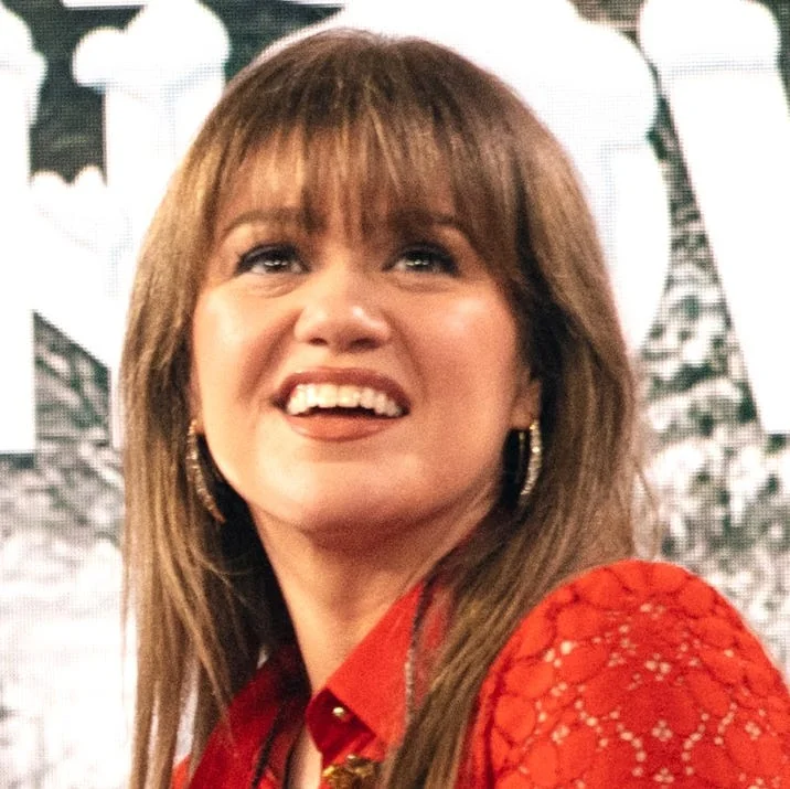 Kelly Clarkson smiling at an event, reflecting her music's impact.