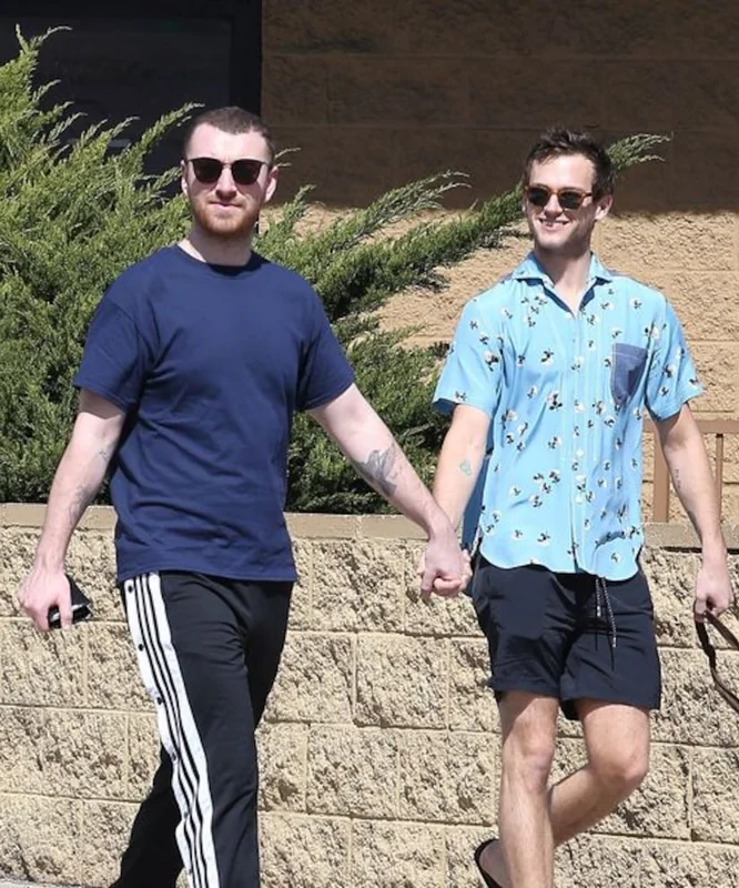Brandon Flynn and Sam Smith holding hands while walking.